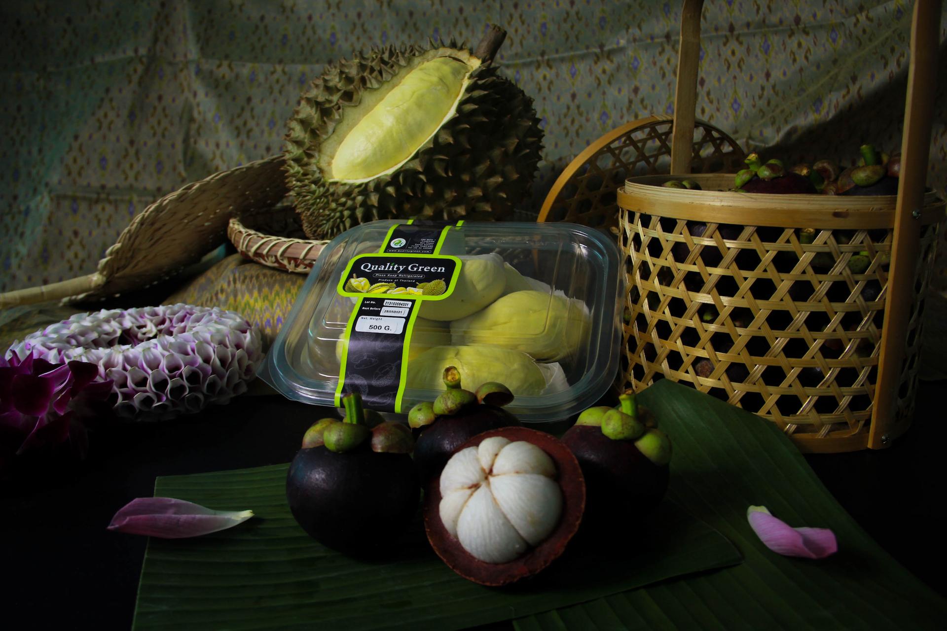 The image showcases a still life arrangement of exotic fruits, including durian and mangosteen. The composition highlights the fruits and their presentation, potentially for sale or display.